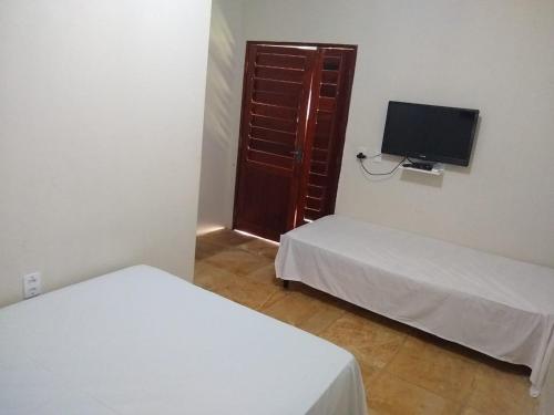 a room with two beds and a tv and a door at Beach House in Flecheiras