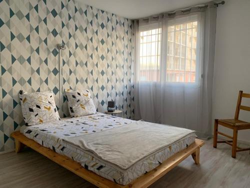 a bedroom with a bed and a window and a chair at Duplex Centre Ville 3 chambres in Alès