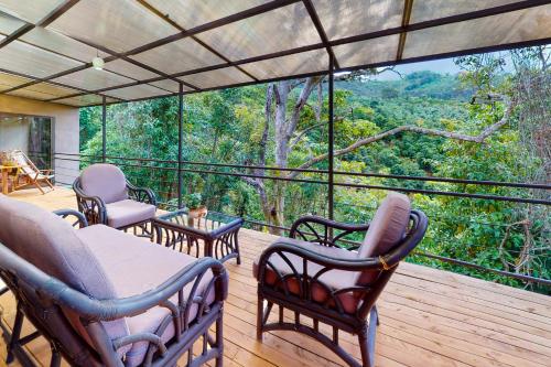 a deck with chairs and tables and a view of the forest at Aqua Tarrazu in Santa Cruz