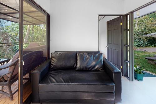 a black leather couch sitting on a porch at Aqua Tarrazu in Santa Cruz