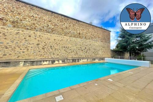 a swimming pool in front of a brick wall with a butterfly sign at Le Renoir terrasse de plain-pied et piscine in Limoges