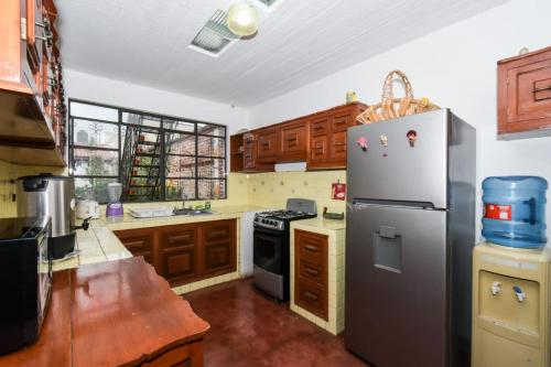 une cuisine avec un réfrigérateur en acier inoxydable et des armoires en bois dans l'établissement Casa Morenita mía, à San Cristóbal de Las Casas