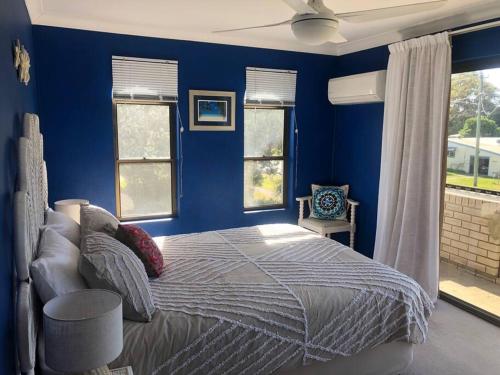 1 dormitorio azul con 1 cama y 2 ventanas en Aloha Iluka! en Iluka