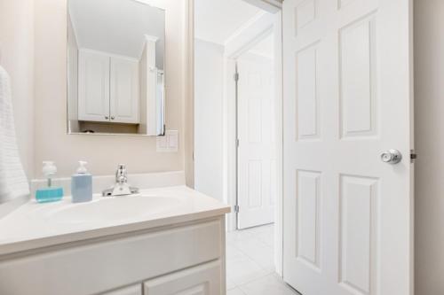 a white bathroom with a sink and a mirror at Dock Holiday in Cudjoe Key