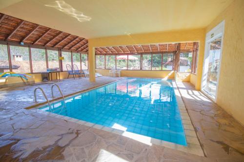 a swimming pool in a house with a large window at VELINN Hotel Ninho do Falcão in Monte Verde