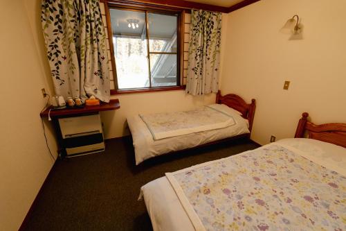 een slaapkamer met 2 bedden en een raam bij ペンションminiモンゴル in Makito