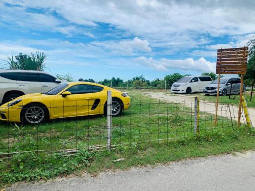 a yellow car parked in a field next to a fence at Nichahome Luxury Villa in Hua Hin