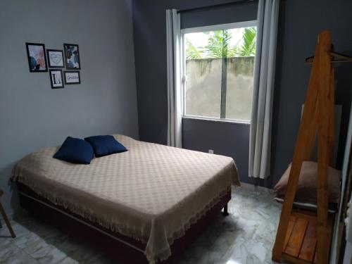 a bedroom with a bed with blue pillows and a window at Flat Solife 2 Cabo Frio-Búzios in Cabo Frio
