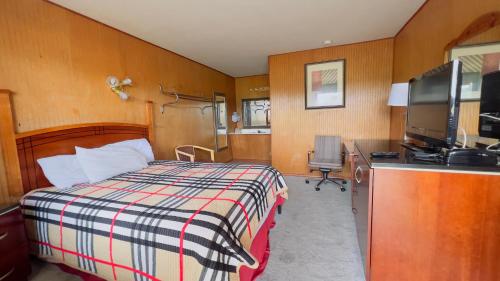 a bedroom with a bed and a desk with a television at Country Inn - Licking in Licking
