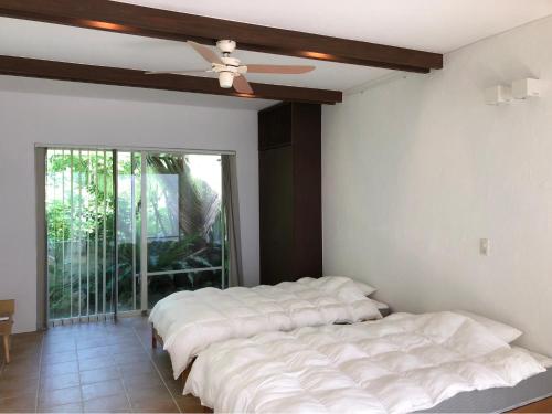 two beds in a room with a ceiling fan at 727セブンツーセブン石垣島ベース in Ishigaki Island