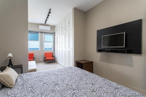 um quarto com uma cama e uma televisão de ecrã plano em Atlântica Palace Vista Mar no Rio de Janeiro