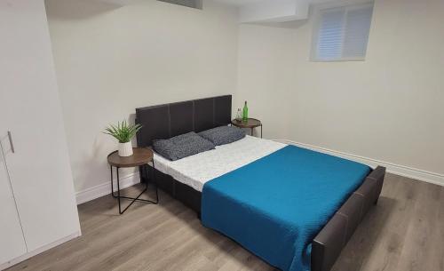 um quarto com uma cama com um cobertor azul e duas mesas em Lake-walk 3 Bed 2 Bath Apartment em Hamilton