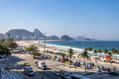 uma praia movimentada com muitos carros estacionados em Atlântica Palace Vista Mar no Rio de Janeiro