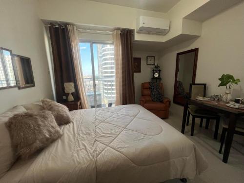 a bedroom with a white bed and a desk and a window at Inspiria Condominium Tower, beside Abreeza Ayala Mall, Davao City in Davao City