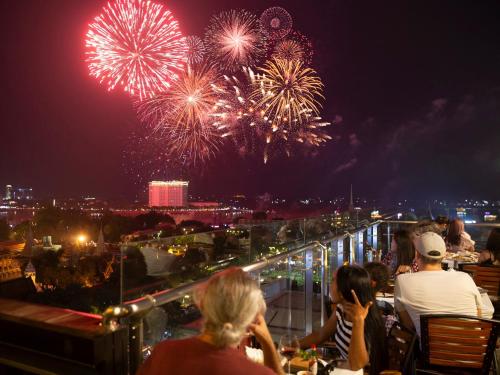 a group of people sitting at a table watching fireworks at Le Botum Hotel in Phnom Penh