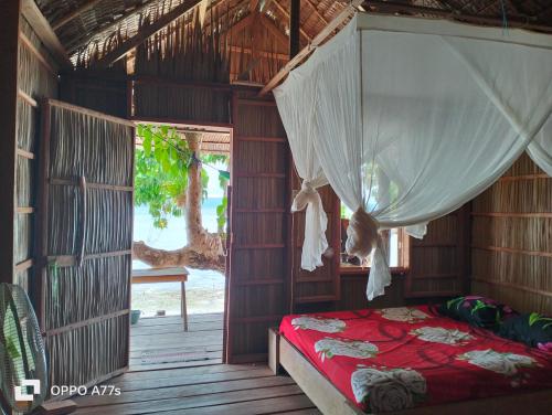 a bedroom with a canopy bed and a porch at Mambetron Homestay Raja Ampat in Pulau Mansuar