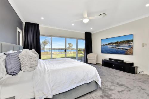 - une chambre avec un grand lit et une grande fenêtre dans l'établissement Lake Palm Resort Luxury Retreat absolute Waterfront on 3 acres at Lake Macquarie., à Dora Creek