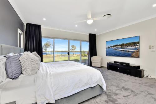a bedroom with a large bed and a large window at Lake Palm Resort Luxury Retreat absolute Waterfront on 3 acres at Lake Macquarie. in Dora Creek