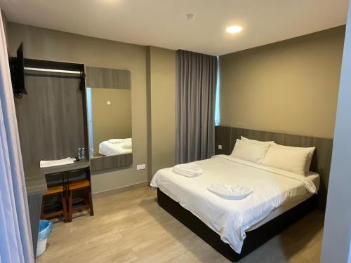 1 dormitorio con cama, escritorio y espejo en Zitro Hotel, en Port Dickson