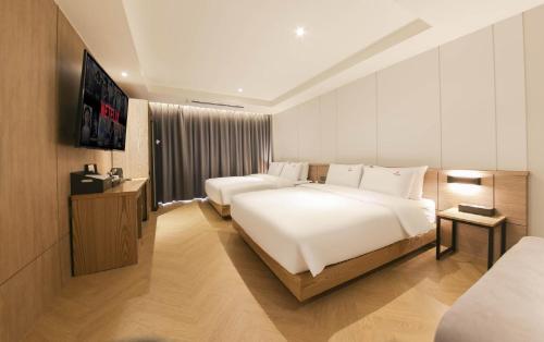 a hotel room with two beds and a television at The Van Hotel in Gimhae