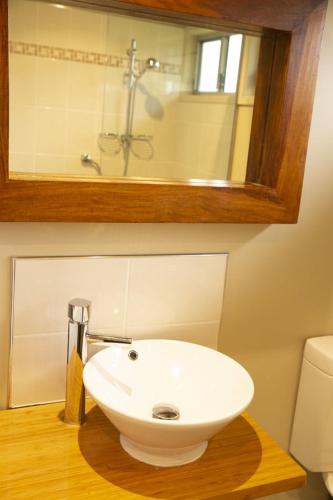 a bathroom with a white sink and a mirror at Little Norfolk Bay Events and Chalets in Taranna