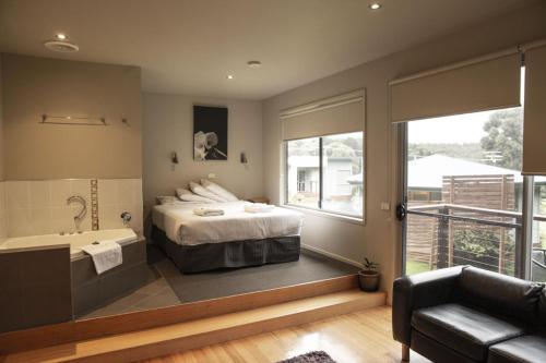 a bedroom with a bed and a tub and a sink at Little Norfolk Bay Events and Chalets in Taranna