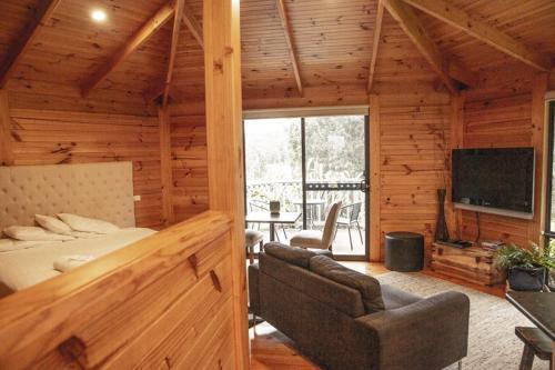 a log cabin bedroom with a bed and a television at Little Norfolk Bay Events and Chalets in Taranna