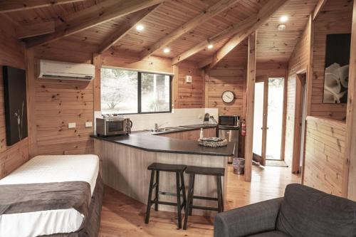 a kitchen in a log cabin with a counter top at Little Norfolk Bay Events and Chalets in Taranna