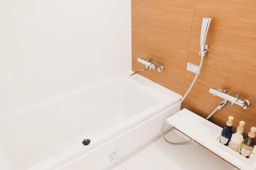 a bathroom with a bath tub with bottles on a shelf at Lampstand STAY Sapporo-House A in Sapporo