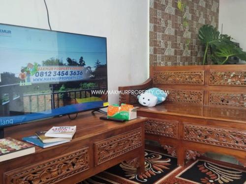 - un salon avec une télévision et un centre de divertissement en bois dans l'établissement Villa Murah di Malang, à Sengkaling