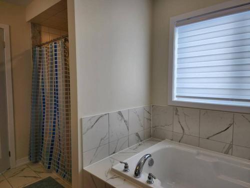 y baño con bañera, ventana y ducha. en Entire home near Hamilton, en Caledonia