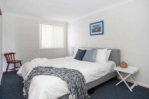a bedroom with a large bed and a chair at Wave Spray in Burrill Lake