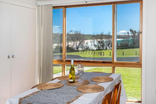 a table with a bottle of wine and glasses and a window at Wave Spray in Burrill Lake
