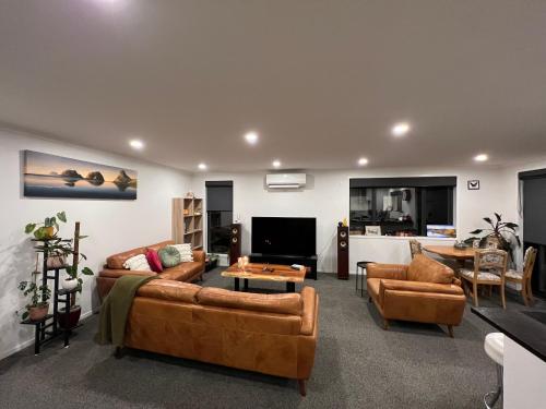Convenient and comfortable Waitara في Waitara: غرفة معيشة مع كنبتين وتلفزيون