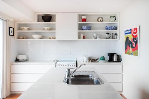 a kitchen with a sink and white cabinets at The Glass House Mollymook Beach in Mollymook