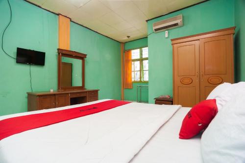 a bedroom with a large white bed with red pillows at Reddoorz Syariah At Hotel Matahari 2 in Jambi