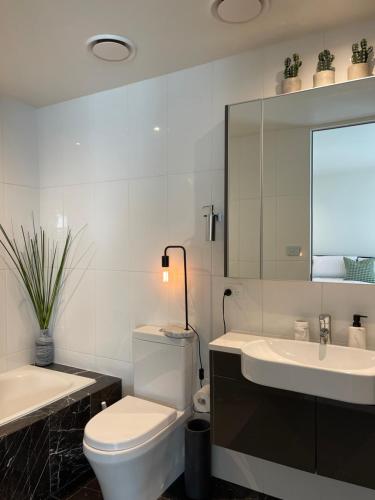 a bathroom with a toilet and a sink and a mirror at Lakeview Luxe - EV charger, Pool, Gym, Location + in Kingston 