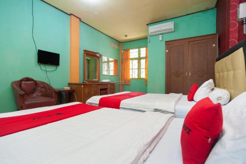 a bedroom with two beds with red and white at Reddoorz Syariah At Hotel Matahari 2 in Jambi