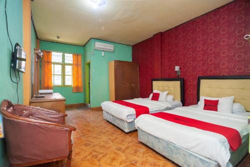 two beds in a room with red and green walls at Reddoorz Syariah At Hotel Matahari 2 in Jambi
