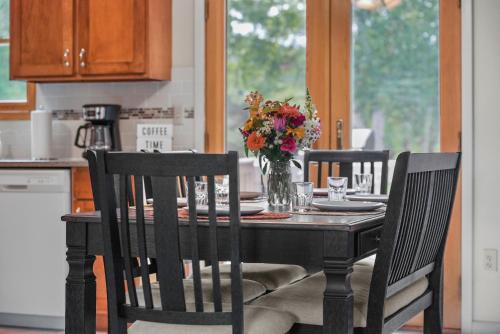 a dining room table with a vase of flowers on it at LAKEFRONT PARADISE 4 bedroom Home w direct lake access, Pets OK in Traverse City