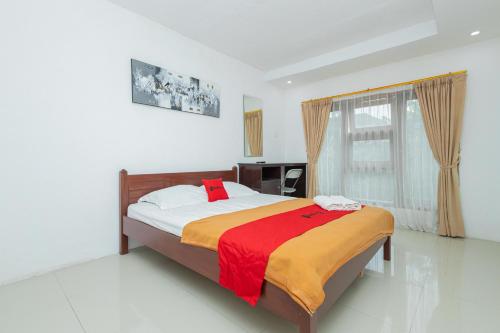 a bedroom with a bed and a large window at RedDoorz Syariah At Wisma Djokorio Poncokusumo in Gubukklakah