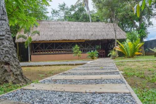 a walkway leading to a building with a straw roof at Kirindioya Village Safari Lodge in Tanamalwila