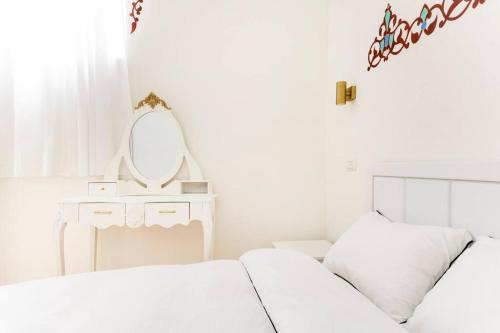 a white bedroom with two beds and a mirror at family home in acre in ‘Akko