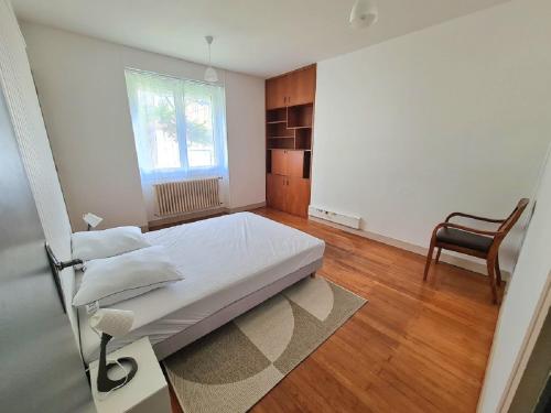 um quarto com uma cama, uma cadeira e uma janela em Aigue Marine et Coquelicot em Jonzac