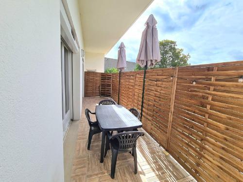 un patio avec une table, des chaises et un parasol dans l'établissement Aigue Marine et Coquelicot, à Jonzac