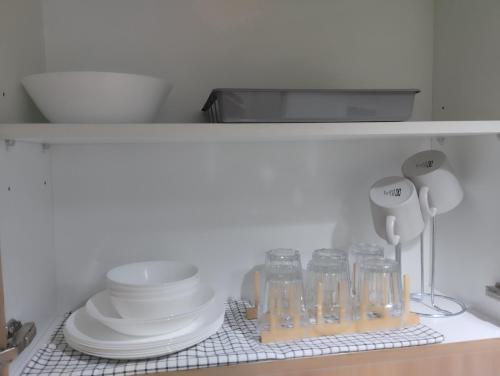 a shelf with plates and cups and dishes on it at Aj booking in Manila