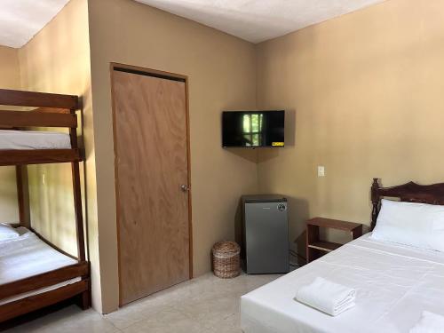 a bedroom with a bed and a television on the wall at Hotel Bacalar Sunshine in Bacalar