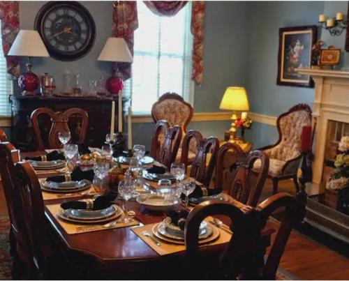 a dining room with a table with chairs and a clock at Governor's Corner Bed & Breakfast in Russellville