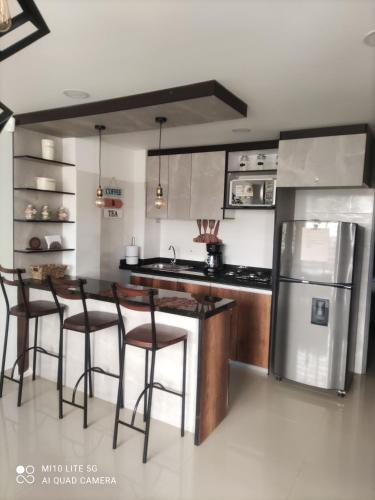 a kitchen with a island with bar stools and a refrigerator at Apartaestudio Maridiaz in Pasto