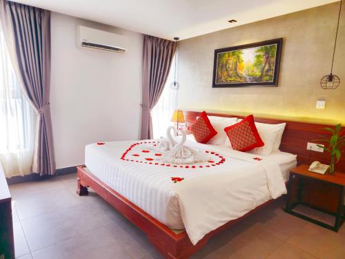 a bedroom with a large white bed with red pillows at Le Botum Hotel in Phnom Penh